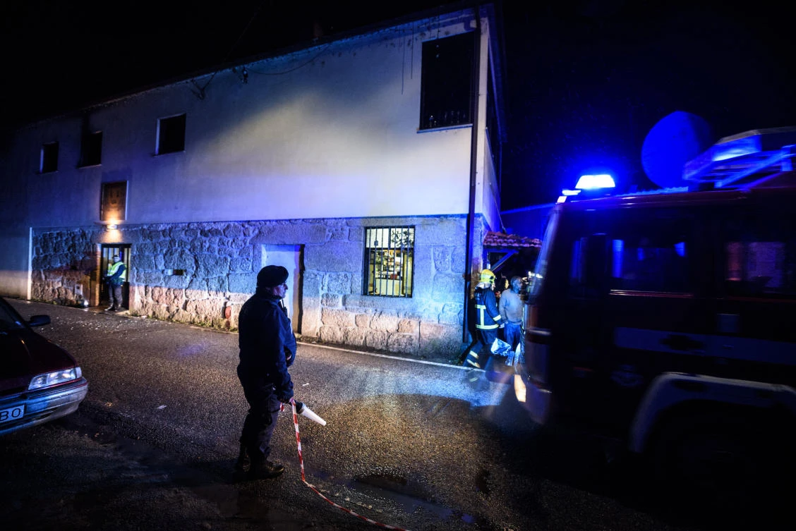 Policemen and firefighters work outside the building, in the background, where a heater exploded killing people in the village of Vila Nova da Rainha, outside Tondela, northern Portugal, in the early hours of Sunday, Jan. 14 2018. A wood-burning stove exploded and started a fire late Saturday at the packed premises of a local residents’ association in the north of Portugal, officials said.(AP/Sergio Azenha)