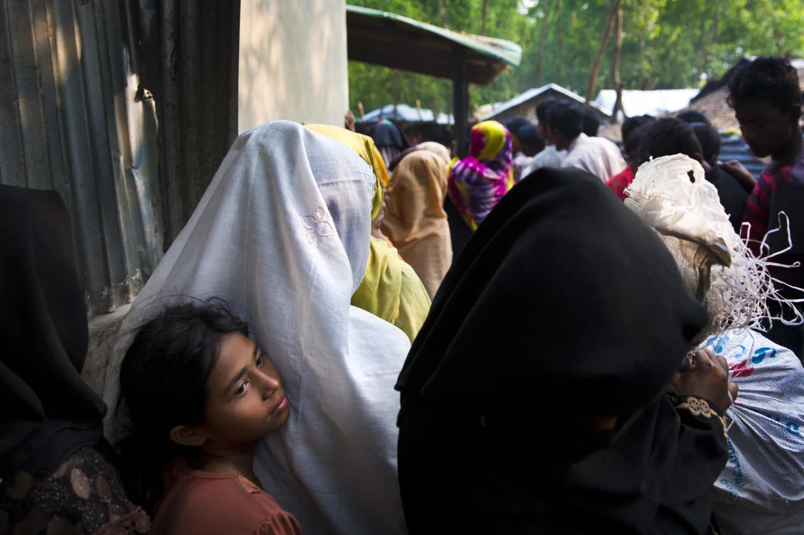 A Rohingya girl clings to her mother as they wait in a queue for rations at Nayapara refugee camp, some 69 kilometers (43 miles) from in Cox bazar, Bangladesh, Saturday, Jan. 13, 2018. (AP/Manish Swarup)