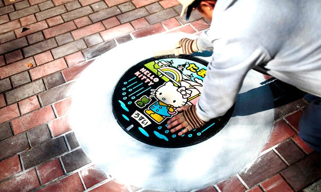 A worker installs a designed manhole cover in Tokyo. (AFP)
