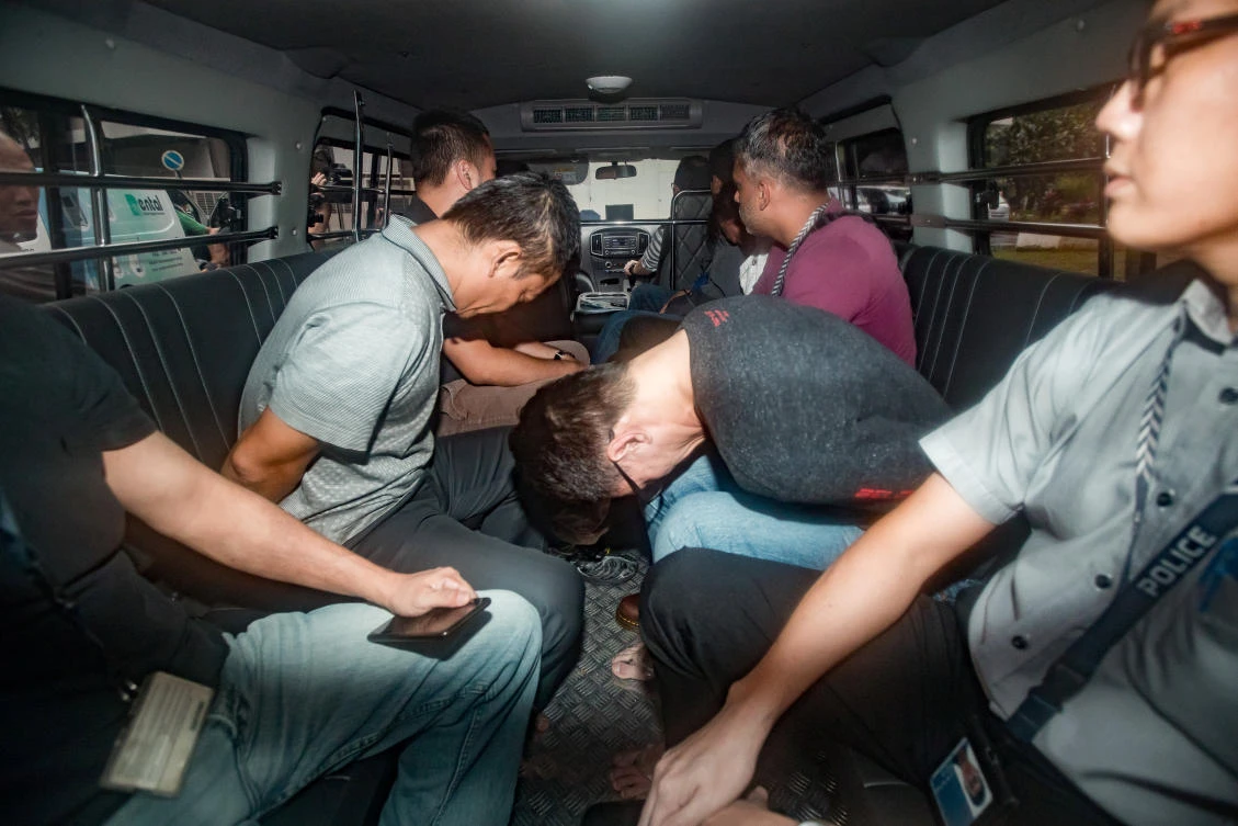 Some of the Singaporean men, eight of whom were employees of the Singapore subsidiary of Royal Dutch Shell, charged with large-scale oil theft arrive in a van at the State Courts. (Reuters)