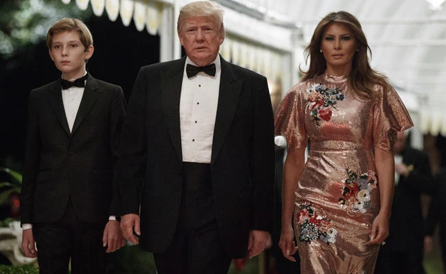 President Donald Trump arrives for a New Year's Eve gala at his Mar-a-Lago resort with first lady Melania Trump and their son Barron, Sunday, Dec. 31, 2017, in Palm Beach, Florida. (AP Photo/Evan Vucci)