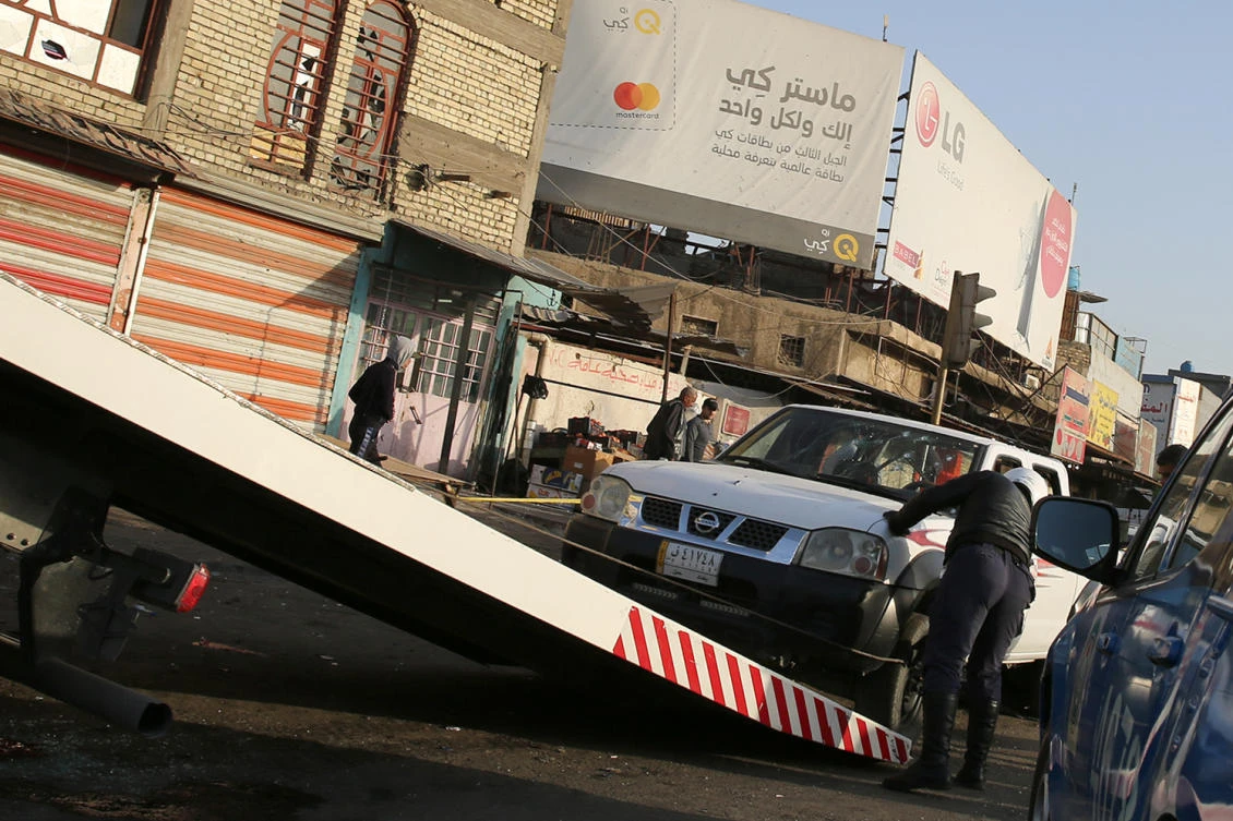 An Iraqi security member inspects a damaged vehicle in the area where a double suicide bombing killed 38 people in central Baghdad on Monday. (AFP)