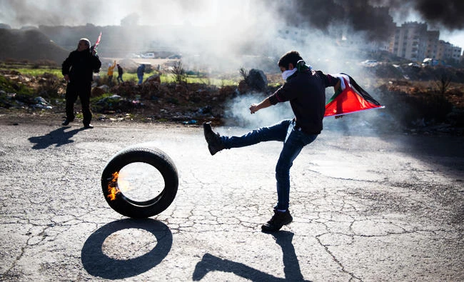 A Palestinian protester kicks a tire following protests against US. President Donald Trump's decision to recognize Jerusalem as the capital of Israel, in the West Bank city of Ramallah. (AP)