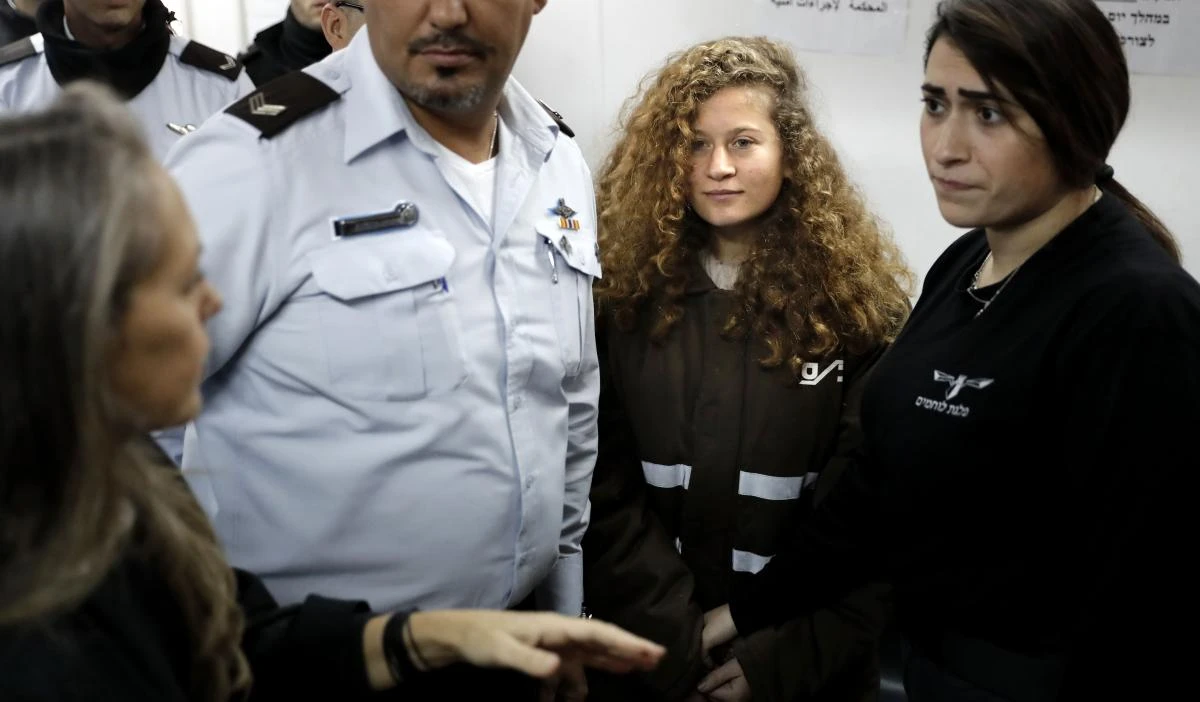 TOPSHOT - Sixteen-year-old Palestinian Ahed Tamimi (2-R), a well-known campaigner against Israel's occupation, stands for a hearing in the Israeli military court at Ofer military prison in the West Bank village of Betunia on January 15, 2018. Ahed Tamimi was charged on January 1 with 12 counts including assault for slapping and kicking Israeli soldiers near her home in the occupied West Bank. The European Union voiced concern earlier in the week over the Israeli detention of Ahed and another Palestinian minor. / AFP / THOMAS COEX