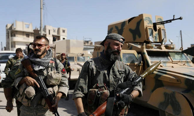 A fighter of the Syrian Democratic Forces (SDF) carries a weapon as he stands near a military vehicle in Raqqa, Syria, Oct. 16, 2017. (REUTERS)