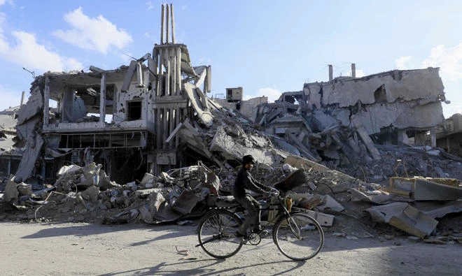 A Syrian boy rides a bicycle past destroyed buildings in the northern Syrian city of Raqqa on Tuesday. (AFP)