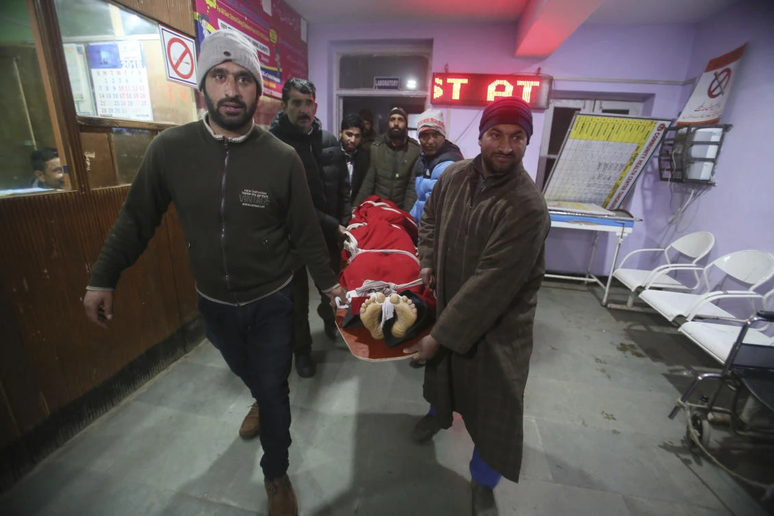 Kashmiri villagers and policemen carry the body of a Swedish skier who has been identified as 25-year-old Daniel Akesson inside a hospital in Tangmarg, near the tourist town of Gulmarg, Jammu and Kashmir. (AP)