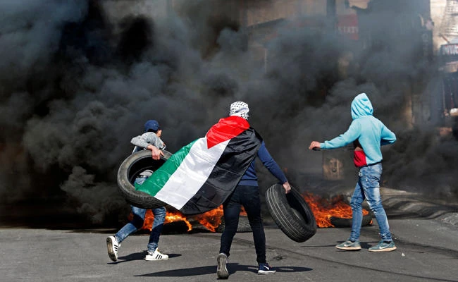 Palestinians protesters burn tires and throw stones toward Israeli forces in the West Bank city of Bethlehem during clashes on January 12, 2018. US Vice President Mike Pence will visit the Middle East this weekend against a backdrop of heightened tensions after Washington’s decisions to recognize Jerusalem as Israel’s capital and to cut funding to Palestinians. (AFP / THOMAS COEX)