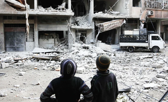 Syrian children look at a building that was damaged in a missile attack on the isolated Kurdish enclave of Afrin in northern Syria. (AFP)