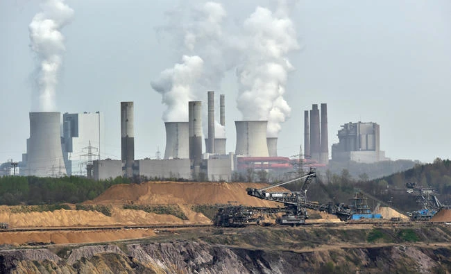 In this April 3, 2014 file photo, machines dig for brown coal at the open-cast mining Garzweiler in front of a smoking power plant near the city of Grevenbroich in western Germany. (AP)