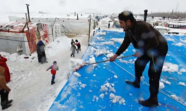 A Syrian refugee removes snow from tents at a makeshift settlement in Bar Elias, in the Bekaa valley. (REUTERS)