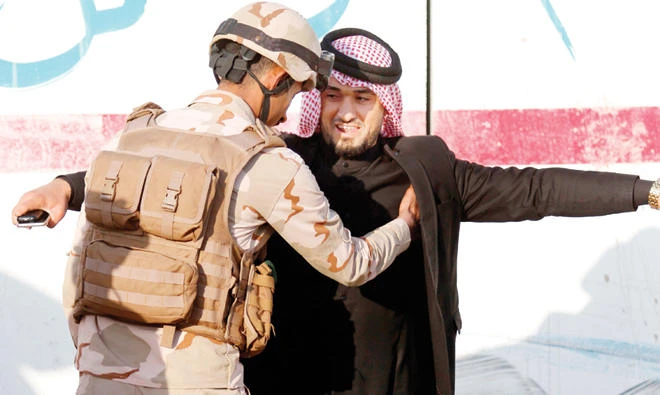 An Iraqi soldier frisks a civilian at a checkpoint near Basra. (File photo/AFP)