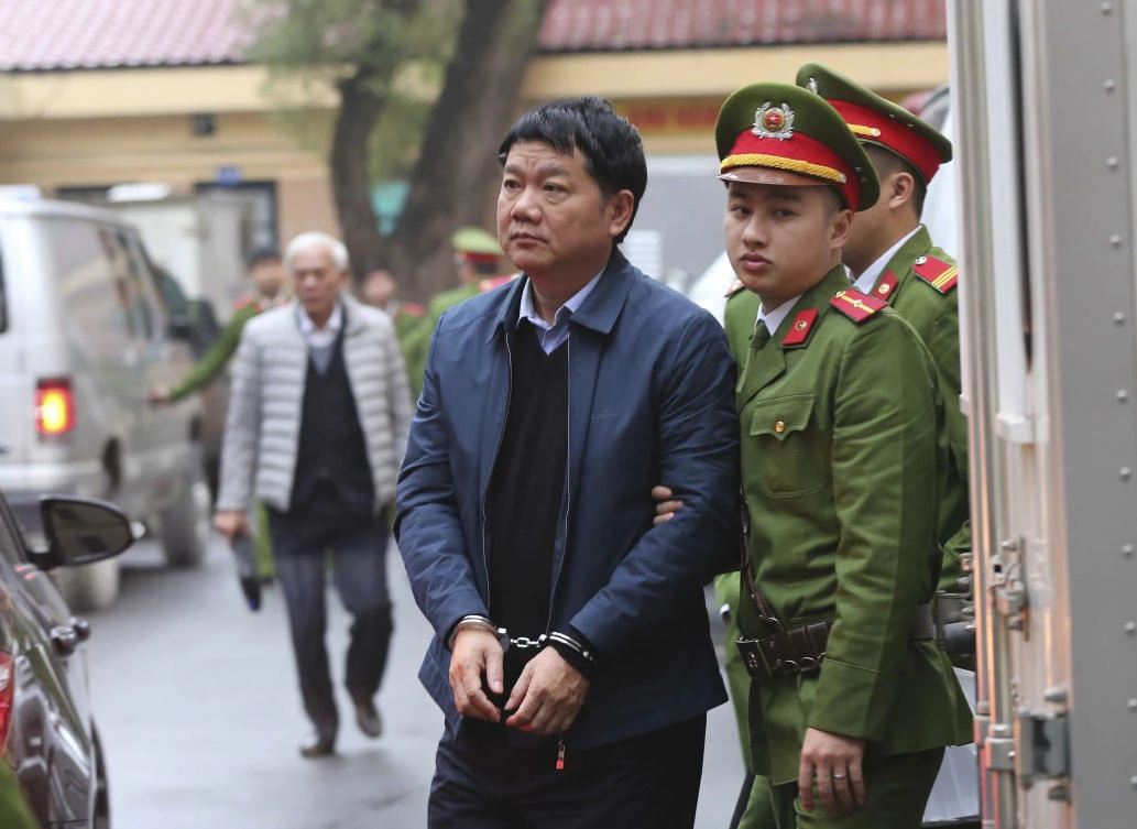 Dinh La Thang, left, is led into a court room by police in Hanoi on January 8. Dinh La Thang, ex-chairman of state energy giant PetroVietnam, was sentenced to 13 years in jail for deliberate economic mismanagement. (AP)