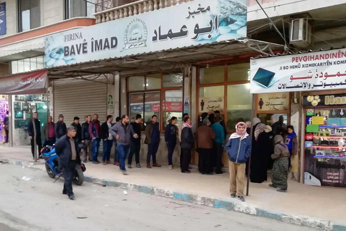 People stand in a queue to enter a bakery in the Syrian northwestern town of Afrin, located in a Kurdish region bordering Turkey, on January 22, 2018. The United Nations said it is ready to help people who might flee from the Afrin enclave, where Turkish troops are on the offensive against Kurdish fighters. (AFP)