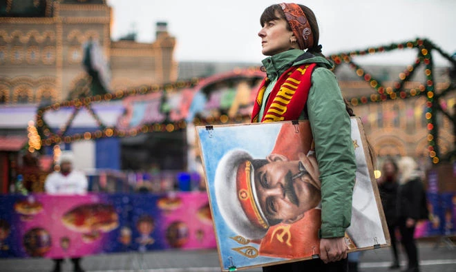 In this file photo, An artist holds a portrait of former Soviet leader Josef Stalin as communist party supporters marking the anniversary of Stalin's birth outside the GUM, State Department store decorated with New Year and Christmas illumination in Moscow's Red Square, Russia. Russia's Culture Ministry on Jan. 23, 2018 has banned the satirical film about Soviet dictator Josef Stalin's death two days before its scheduled release. (AP)