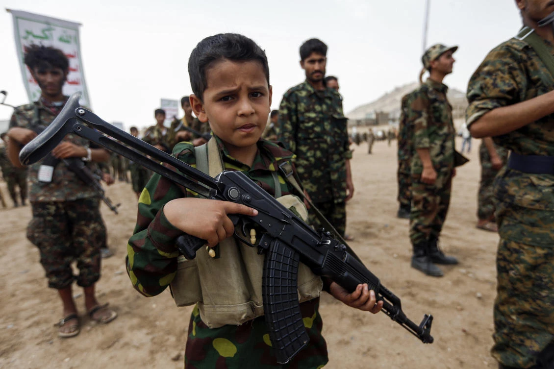 This july 16, 2017 file photo shows a Yemeni boy posing with a Kalashnikov assault rifle during a gathering of newly-recruited Houthi terrorist fighters in the capital Sanaa. (Mohammed Huwais/AFP)