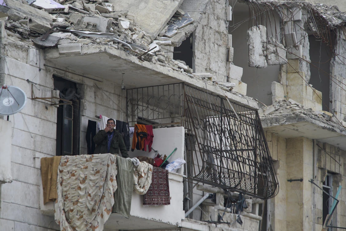 Above, a man smokes in the window of a house damaged by shelling in Aleppo. Thirteen months after government forces captured eastern rebel-held neighborhoods of Aleppo, life in the city has improved drastically with more security and more supplies of water and electricity. (AP)