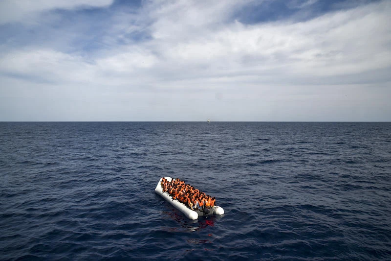 Migrants and refugees on a rubber boat wait to be evacuated during a rescue operation. (AFP)