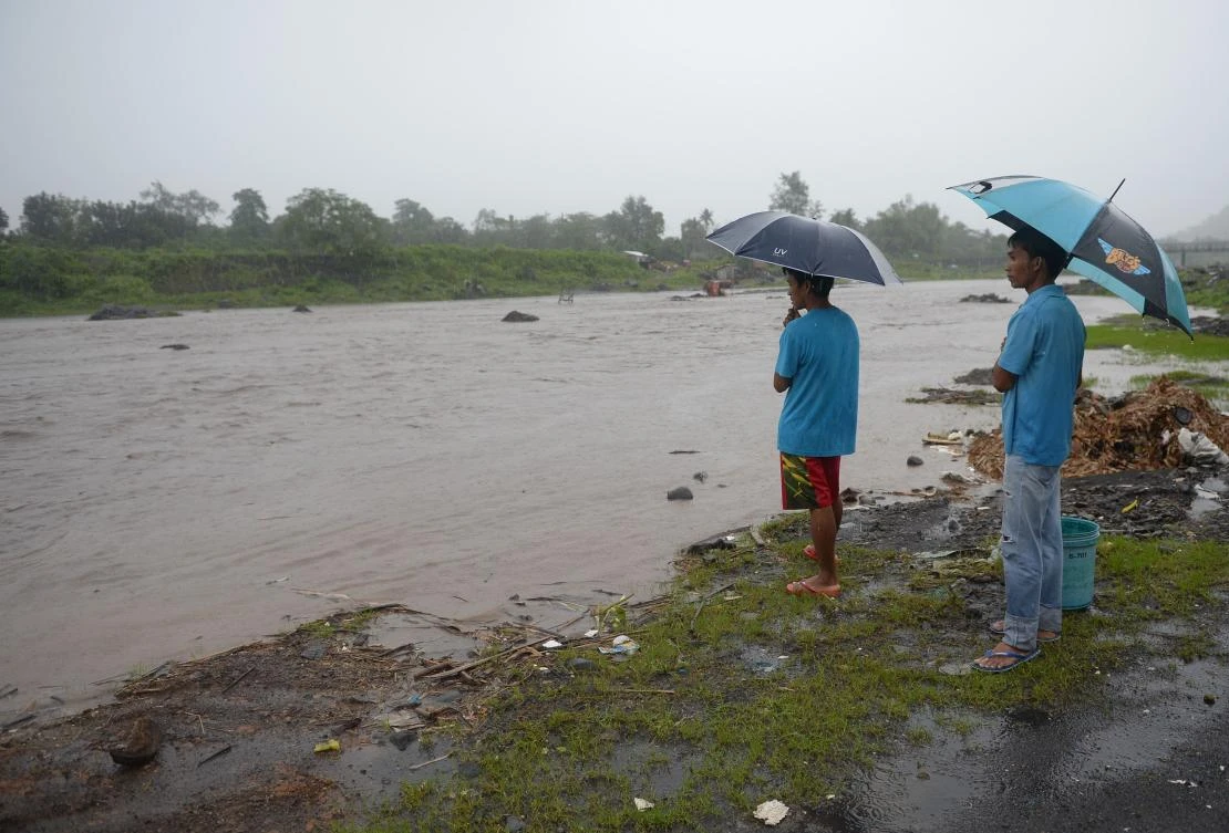 Residents, holding umbrellas, watch the current of a river near Mayon volcano in Daraga town, Albay province, south of Manila on January 27, 2018, as heavy rains pounded areas near the volcano. (AFP)