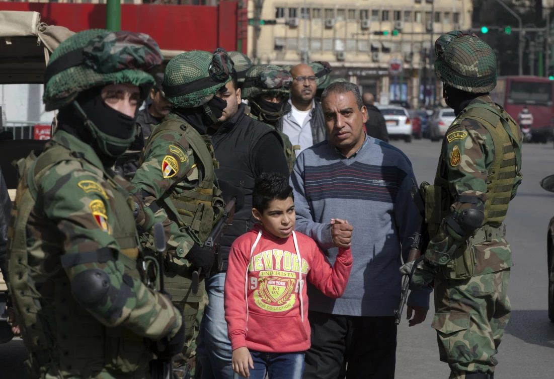 In this file photo, people walk by a special forces soldiers guard in front of the National Election Authority, which is in charge of supervising the 2018 presidential election in Cairo, Egypt.(AP)