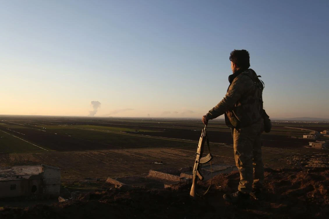 A Syrian rebel-fighter stands in the Tal Malid area, north of Aleppo, as he watches smoke billow from a Kurdish People’s Protection Units (YPG) position in the area of Afrin, on January 20, 2018. (AFP)