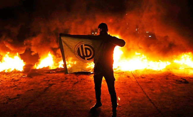 A supporter of Lebanese Parliament Speaker Nabih Berri, holds the Amal party flag during a protest in Beirut, Lebanon. (AP)