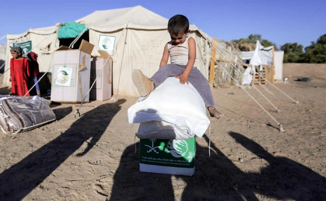 A displaced Yemeni child sits on boxes and sacks of Saudi-provided humanitarian food aid at a camp in Yemen's northeastern province of Marib on January 26, 2018. (AFP / ABDULLAH AL-QADRY)