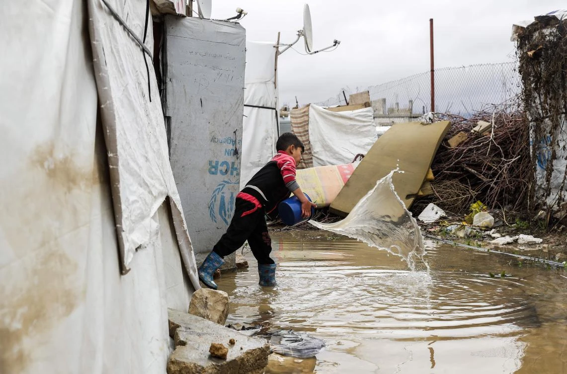 A Syrian child uses a bucket to bale out water from his tent at a refugee camp on the outskirts of the town of Zahle in Lebanon's Bekaa Valley. (AFP)