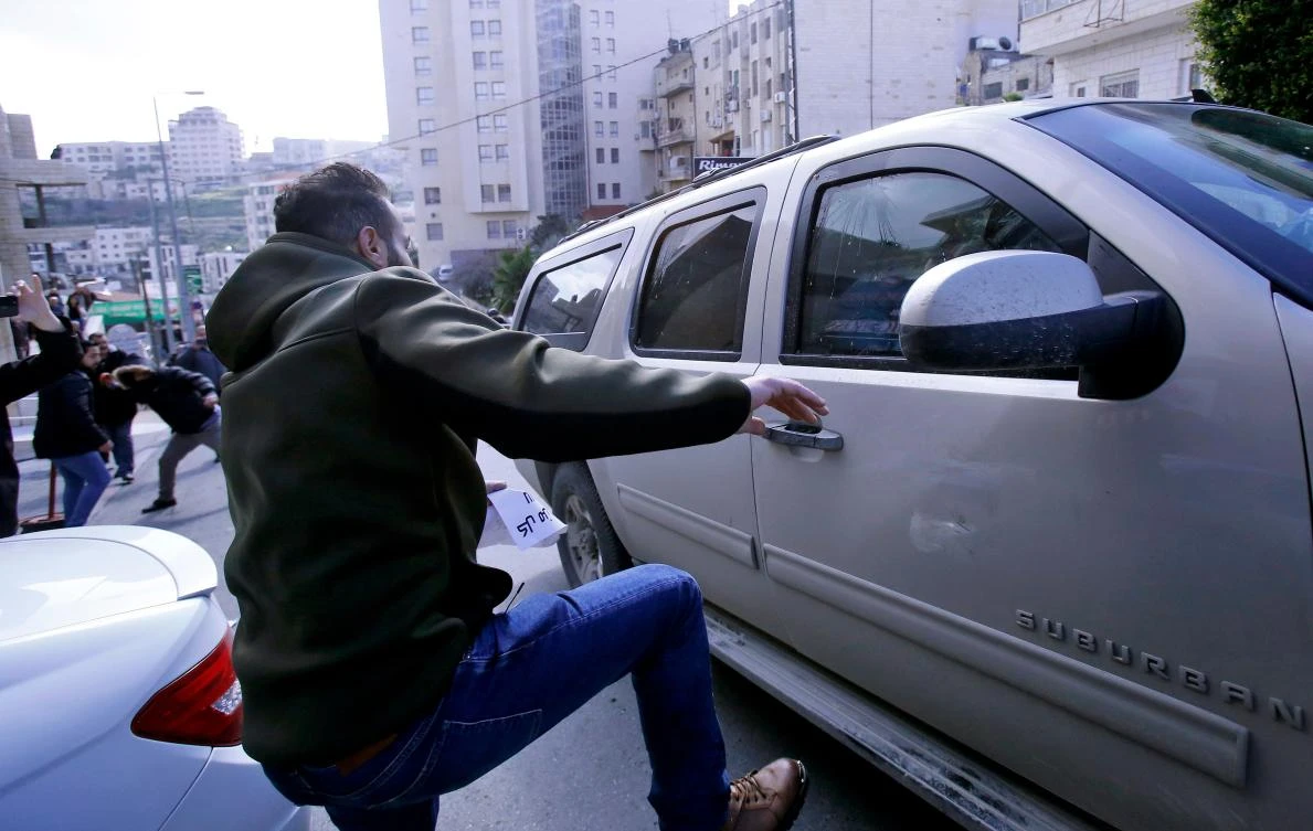 A Palestinian activist kicks a vehicle transporting members of an American economic delegation that are meeting with the Head of the Bethlehem Chamber for Commerce and Industry alongside Palestinian businessmen in the West Bank town. (AFP)