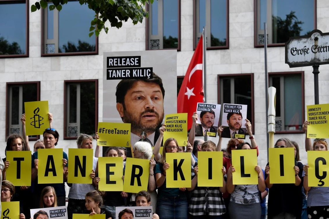 This file photo taken on June 15, 2017 shows Amnesty International activists holding a portrait of the head of Amnesty International in Turkey, Taner Kilic as they stage a protest against his detention in Turkey, in front of the Turkish Embassy in Berlin. An Istanbul court on January 31, 2018 ordered the conditional release of Taner Kilic. A total of 11 activists including Kilic went on trial in Istanbul on terror charges which the rights watchdog said were “baseless allegations.” (John MacDougall / AFP)