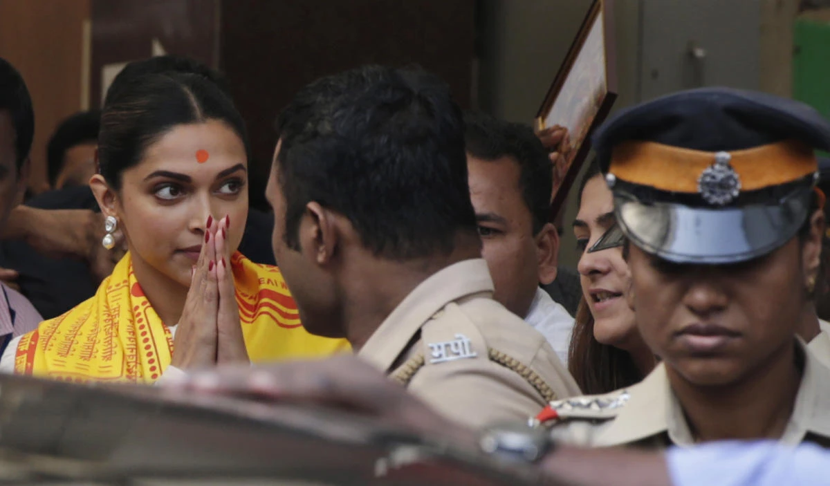 Bollywood actor Deepika Padukone, left, greets media as she leaves after offering prayers at a Hindu temple ahead of the release of her upcoming film "Padmaavat" in Mumbai, India. (AP)