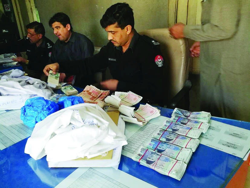 Policemen at Pishtakhara police station with the seized fake currency. (AN photo)