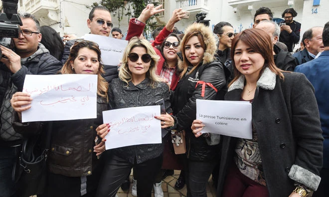 Tunisian journalists wearing red armbands protest with signs outside the headquarters of the National Union of Tunisian Journalists (SNJT) against police threats and intimidation in the capital Tunis on Friday. (AFP)
