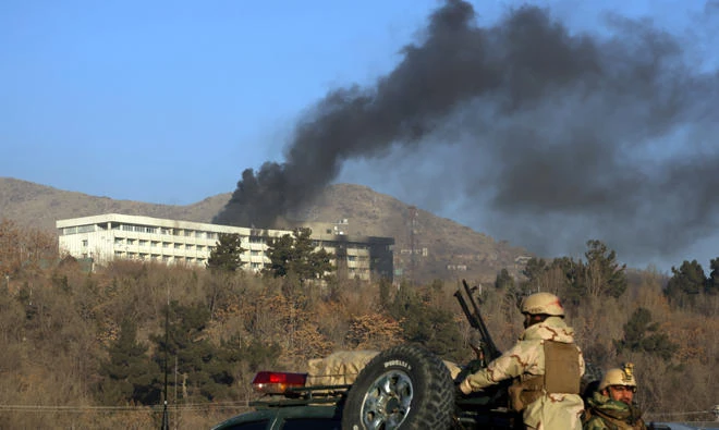 Afghan security personnel stand guard as black smoke rises from the Intercontinental Hotel after an attack in Kabul, Afghanistan. (AP)