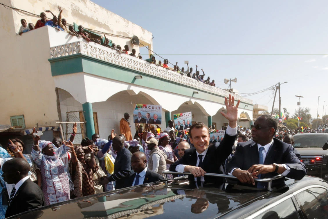 Senegalese President Macky Sale and French President Emmanuel Macron wave from their car in Saint Louis, Senegal, Feb. 3, 2018. (Reuters)