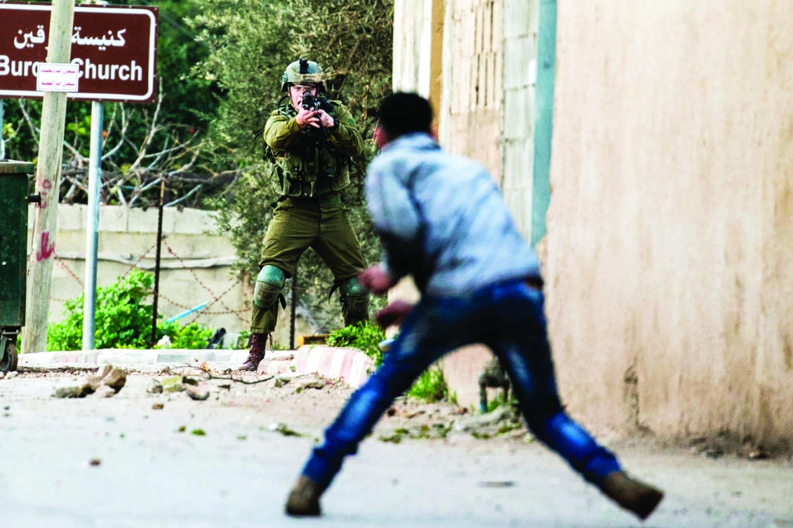 A Palestinian protester confronts an Israeli soldier during an army search operation in the Palestinian village of Burqa, about 18 km northwest of Nablus in the occupied West Bank, on Saturday. (AFP)