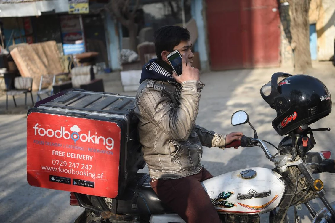 In this photo taken on January 16, 2018 Afghan courier Sarajuddin talks on a phone with a customer as he tries to find an address on a motorbike on a street in Kabul. (AFP)