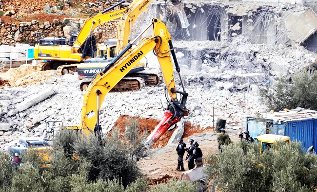 Israeli machineries demolish two under-construction Palestinian residential buildings in the West Bank town of Biet Jala, near Bethlehem on Sunday. (Reuters)