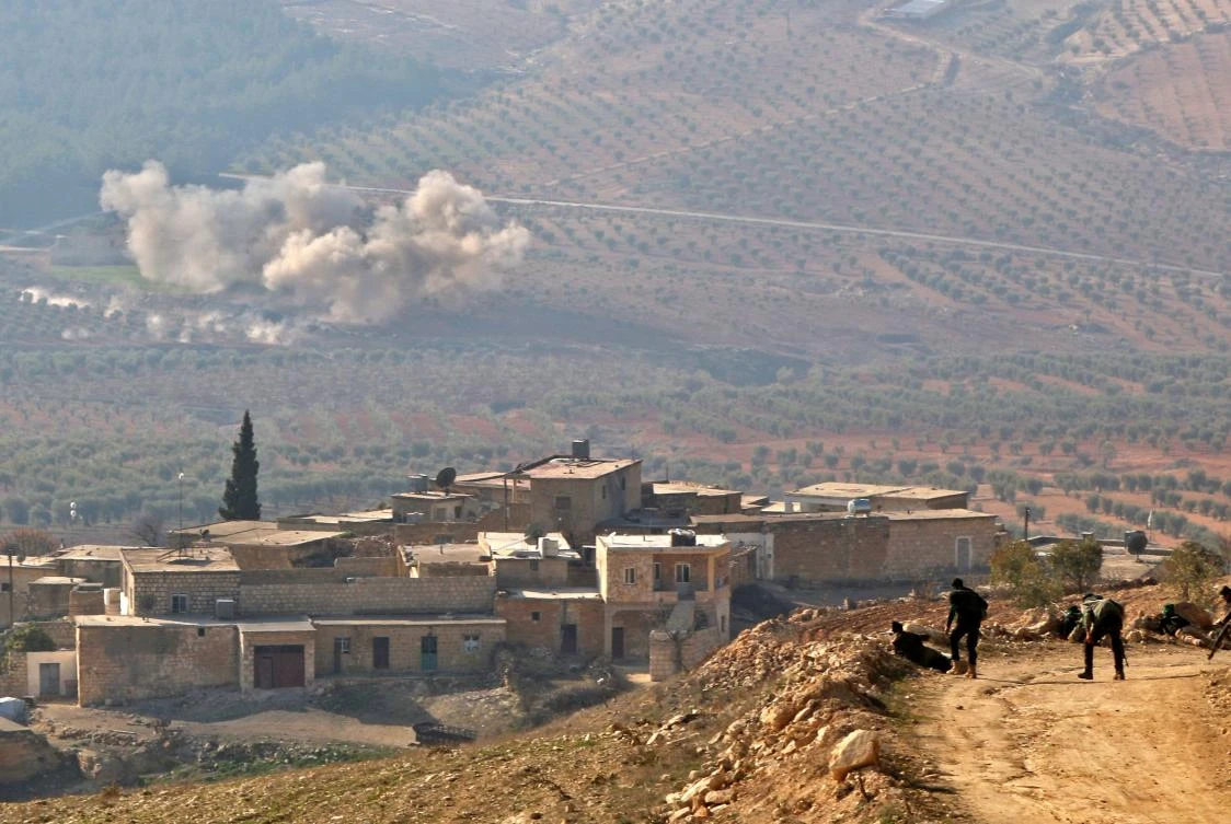 A picture taken on February 5, 2018, on a mountain on the Syrian-Turkish border, north of Azaz, shows Turkish-backed Syrian rebels watching as smoke billows in the village of Al-Amud following artillery shelling. (AFP)