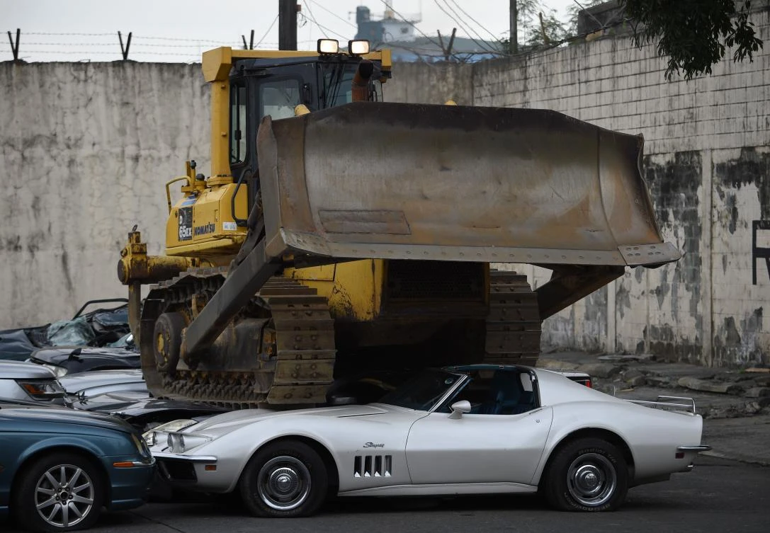 A bulldozer destroys condemned smuggled luxury cars, which include used Lexus, BMW, Mercedes-Benz, Audi, Jaguar and a Corvette Stingray, as part of a drive to fight corruption at the Philippines’ customs bureau. (AFP)