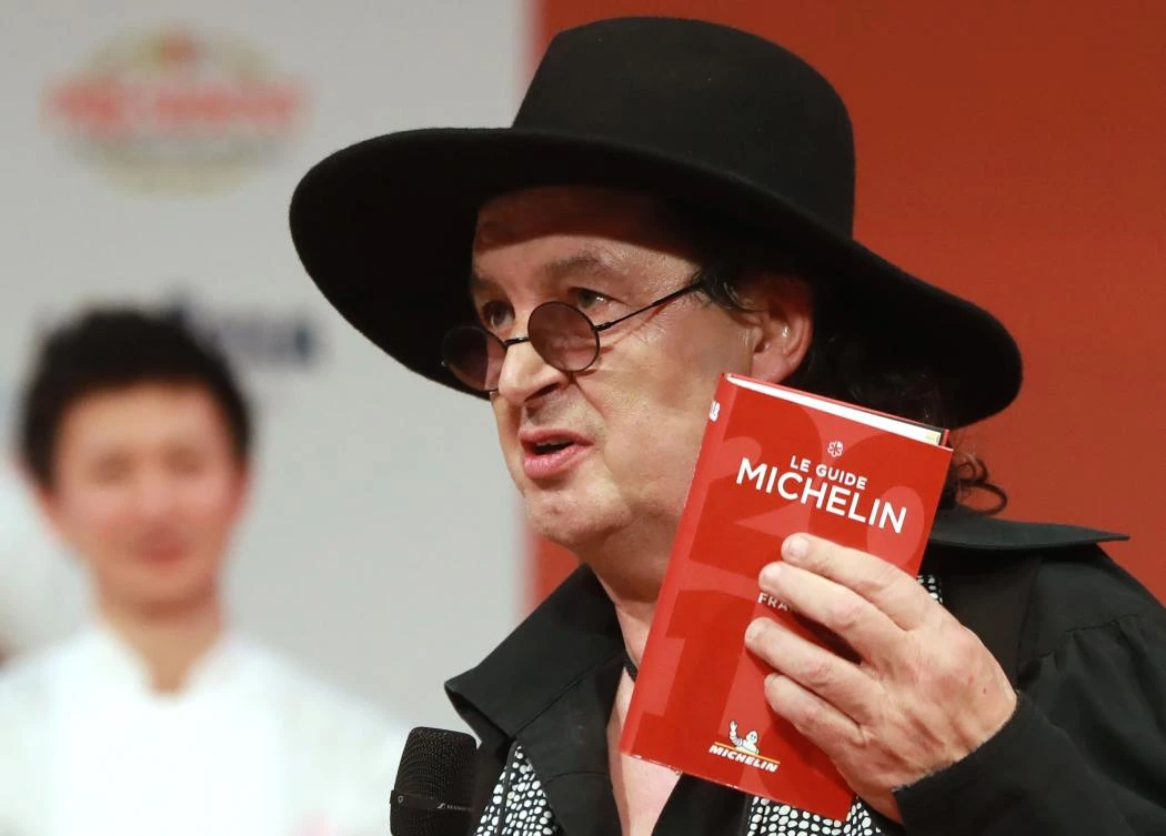 French chef Marc Veyrat, holds a Michelin guide after being awarded the maximum three Michelin stars, during the Michelin guide award ceremony at La Salle Musicale in Boulogne-Billancourt near Paris on February 5, 2018. (AFP)