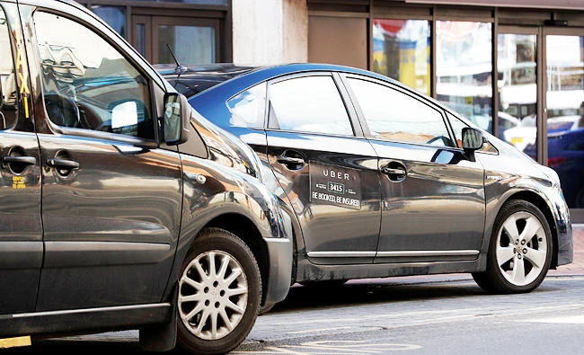 An Uber taxi and a black cab wait outside a hotel in Birmingham, Britain on Monday. (REUTERS)