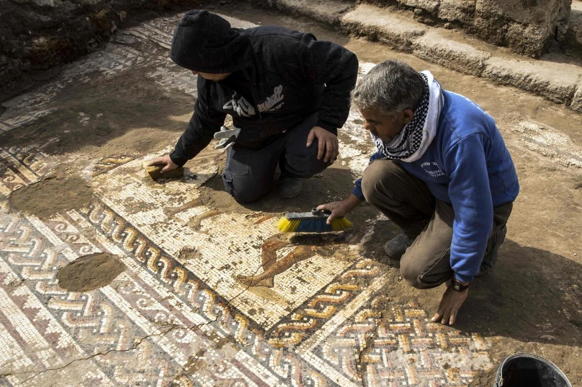 Workers from the Israeli Antiquity Authority clean a rare Roman mosaic from the 2nd–3rd centuries at Caesarea National Park. (AFP)