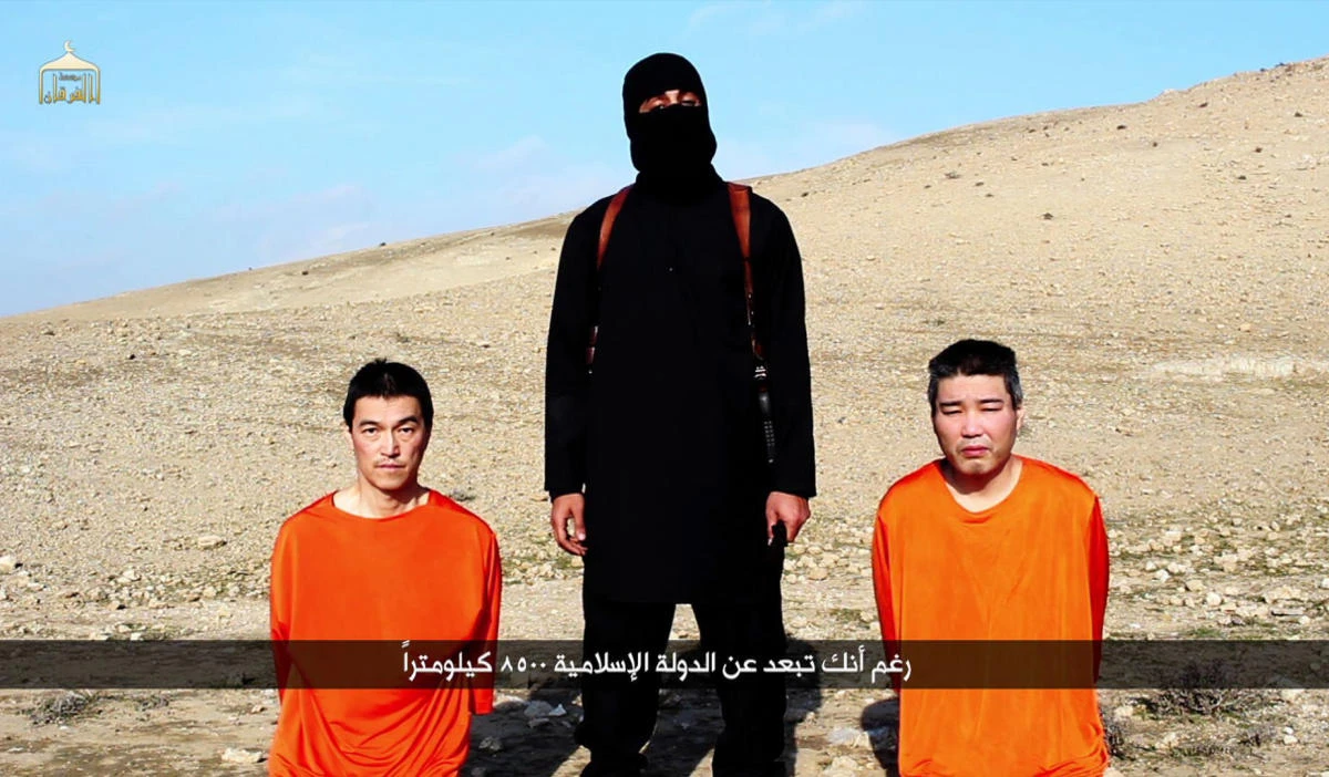 An image grab taken off a video on January 20, 2015, reportedly released by Daesh through Al-Furqan Media, allegedly shows Japanese hostages Kenji Goto (L) and Haruna Yukawa (R) at an undisclosed location. The Daesh group threatened to kill the two Japanese hostages unless Tokyo pays a $200 million ransom within 72 hours to compensate for non-military aid. (AFP)