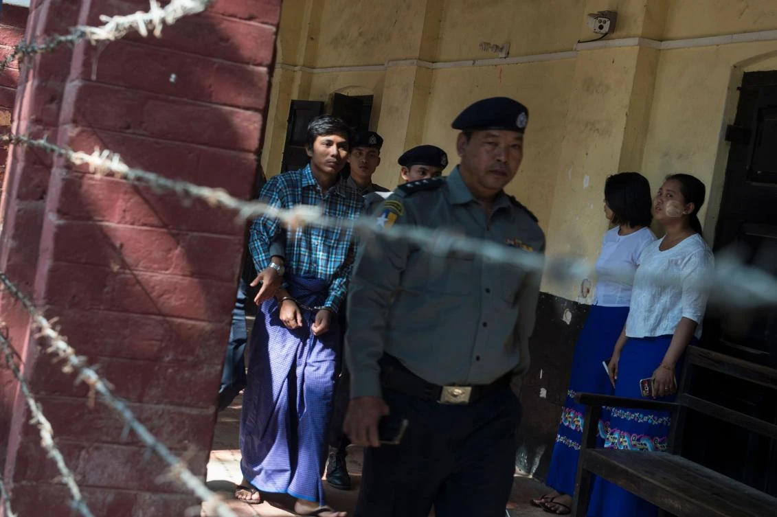 Detained Myanmar journalist Kyaw Soe Oo, left, is escorted by police to a court in Yangon to face trial on February 6. (AFP)