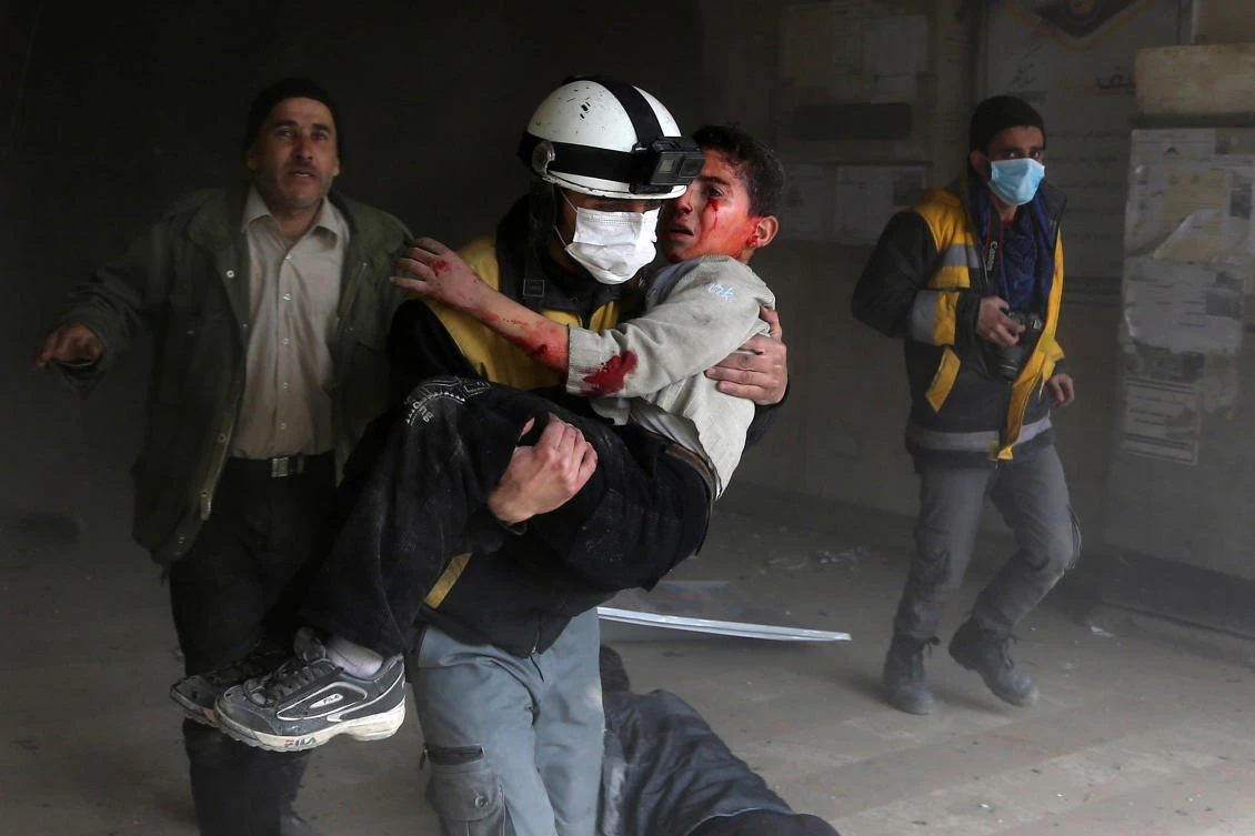 A member of the Syrian civil defence carries a wounded child from the rubble after a reported regime air strike in the rebel-held town of Jisreen. (AFP)