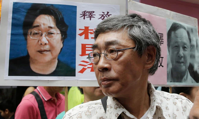 Hong Kong bookseller Lam Wing-kee stands next to a placard with picture of missing bookseller Gui Minhai, in front of his book store in Hong Kong as the protesters are marching to the Chinese central government's liaison office. Sweden has condemned China's "brutal" detention of a Swedish citizen who sold politically sensitive books and whose seizure while he traveled with diplomats stunned Western governments. (File photo/AP)