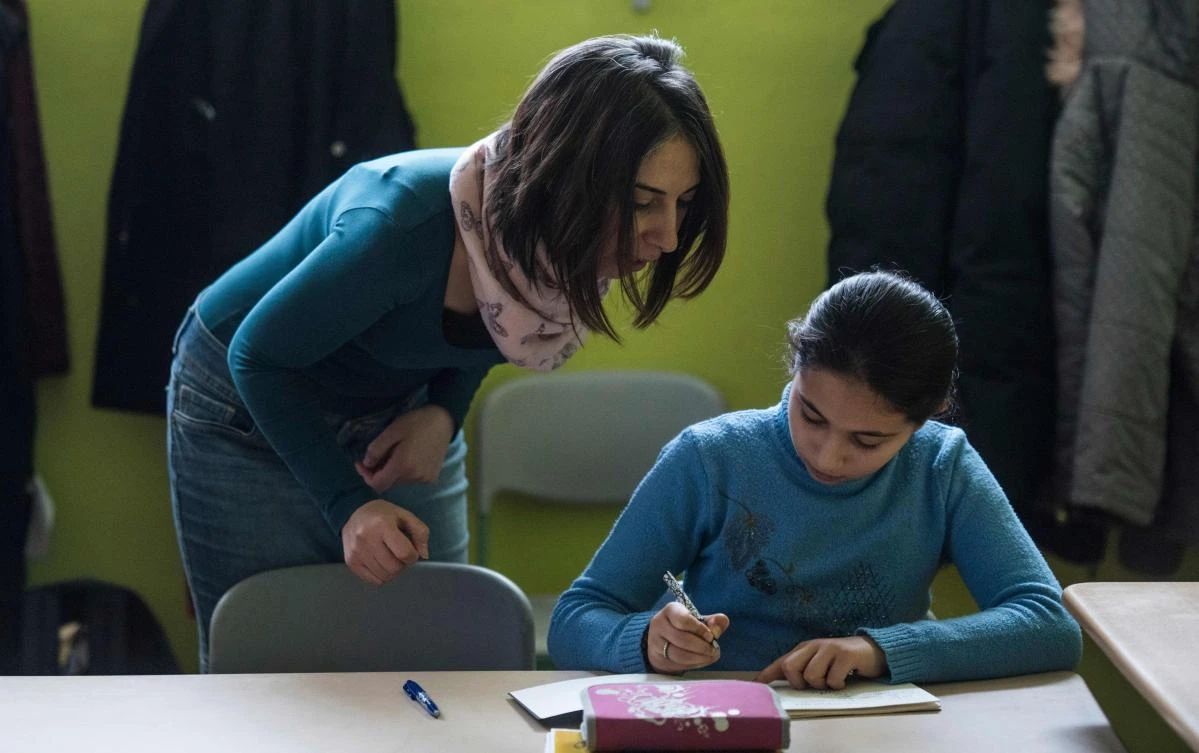 Syrian teaching assistant Hend Al Khabbaz (L) coaches a young Syrian refugee pupil during class at the Sigmund-Jaehn-Grundschule (primary school) in Fuerstenwalde, eastern Germany, on January 19, 2018. (AFP)