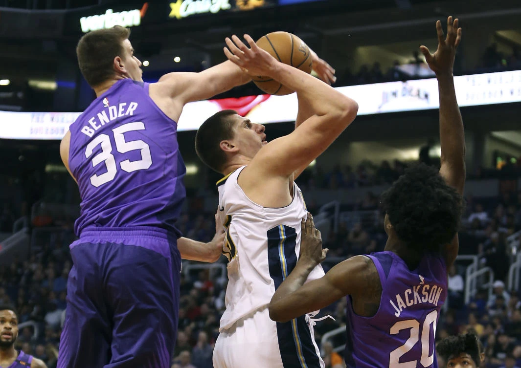 Denver Nuggets’ Nikola Jokic, center, is fouled as he shoots between Phoenix Suns’ Dragan Bender (35) and Josh Jackson during the first half of an NBA basketball game Saturday, Feb. 10, 2018, in Phoenix. (AP)