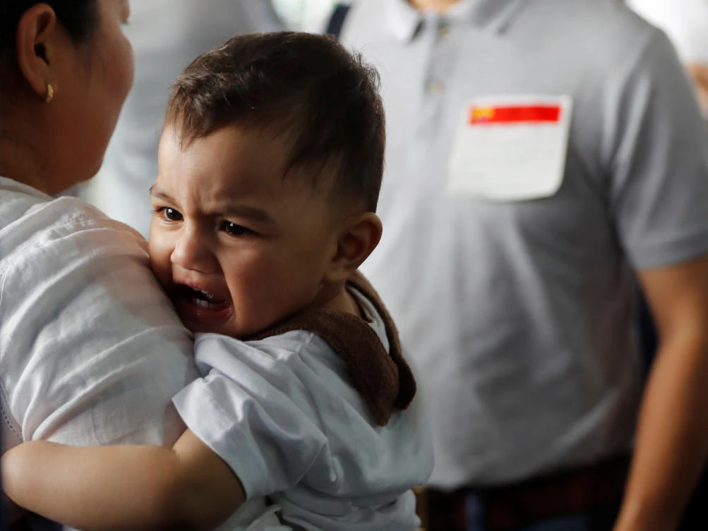 A Filipino worker who was repatriated from Kuwait carries her child upon arrival at Ninoy Aquino International Airport in Paranaque, Metro Manila, Philippines February 12, 2018. (Reuters)